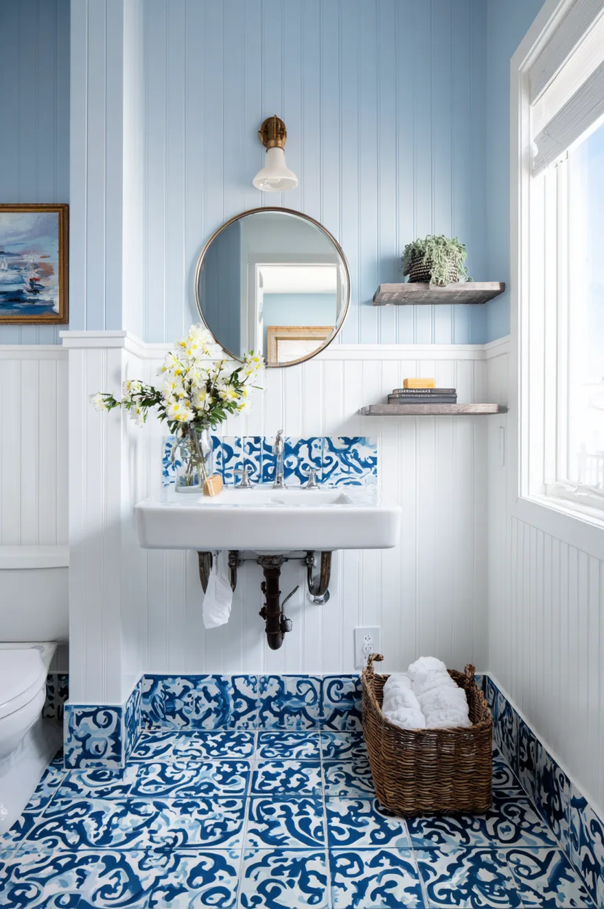 A bright guest bathroom featuring a diamond patterned floor in terracotta, grey, and white, alongside a light oak vanity and a black framed mirror.