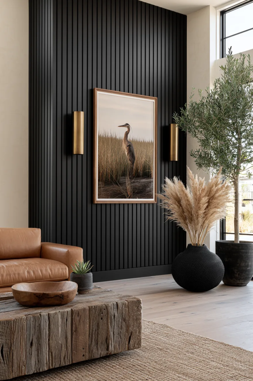 Floor-to-ceiling narrow black wood slat wall with a framed fine-art photography print and minimal cylindrical brass sconces.